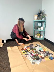 Brittany in Marketing helping coordinate this earth day mural for Grace. She applies labels to the label collage background of the mural.